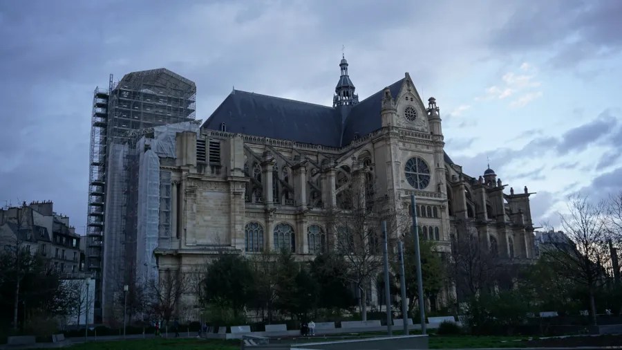 20230324_Frankreich_Paris (211) Large historic church building with Gothic architecture under a cloudy sky at dusk