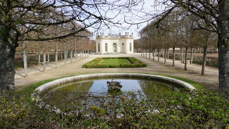 20230325_Frankreich_Paris (165) Small classical pavilion at the end of a symmetrical garden path with trimmed hedges and leafless trees