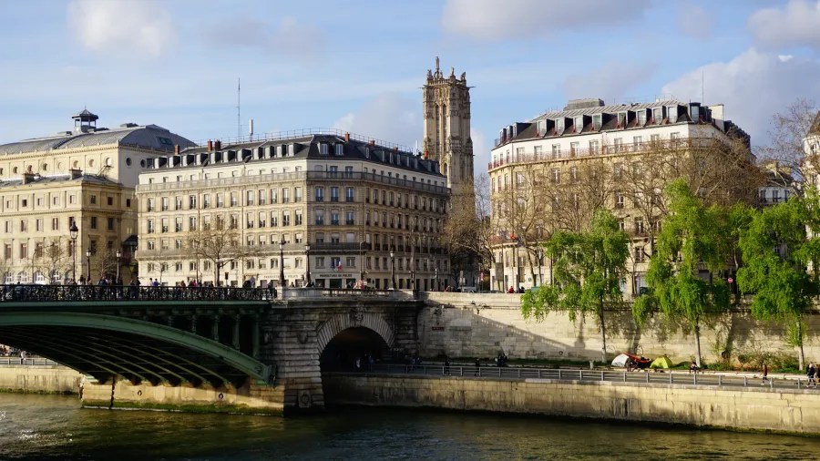 20230325_Frankreich_Paris (208) Bridge over a river with historic Parisian buildings and trees in the background under a clear sky