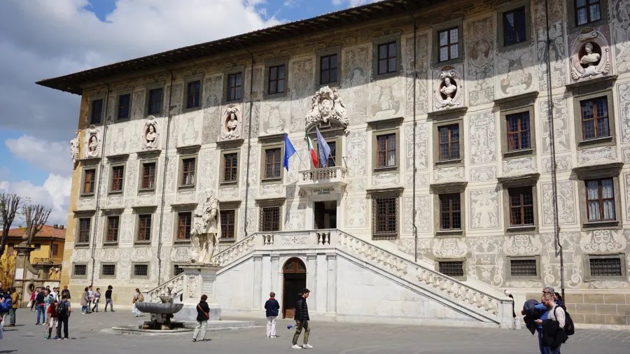 20230420_Italien_Toskana_Pisa (77) Historic building with detailed facade, statue, and people walking in the plaza