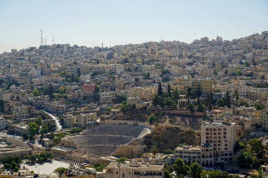 View of a densely built city on a hillside with a large ancient amphitheater in the foreground