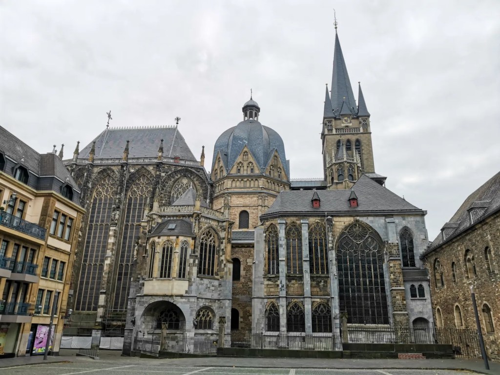 Exterior view of a large historic Gothic cathedral with ornate stained glass windows and a tall spire under a cloudy sky