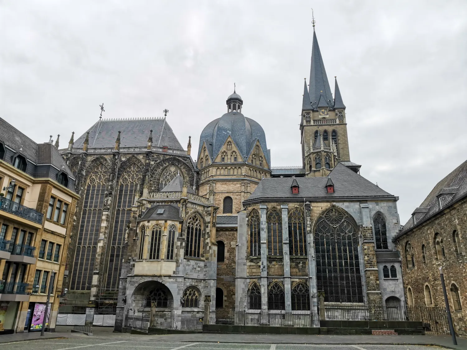 Exterior view of a large historic Gothic cathedral with ornate stained glass windows and a tall spire under a cloudy sky