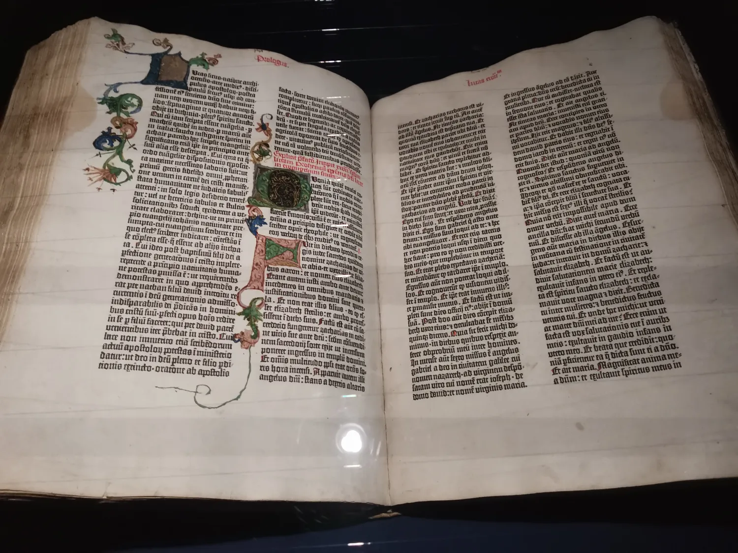 Open medieval manuscript with Latin text and colorful illuminated initials
