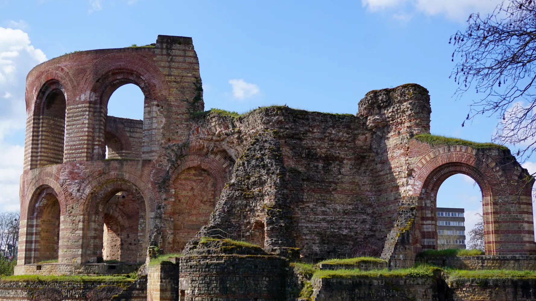 Ancient stone ruins with large arches and partial walls under a blue sky