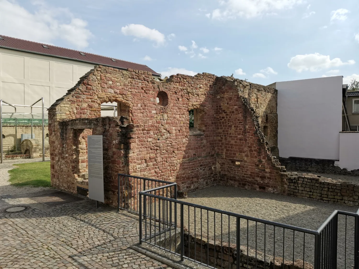 Ruins of an old red brick building with partially standing walls and several window openings under a blue sky