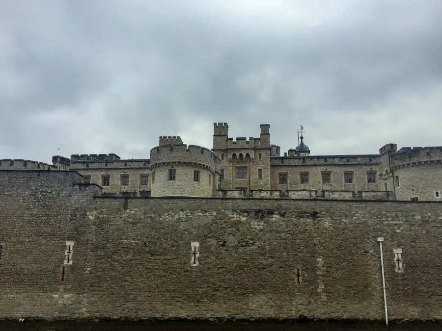 Stone castle with fortified walls and towers under cloudy sky