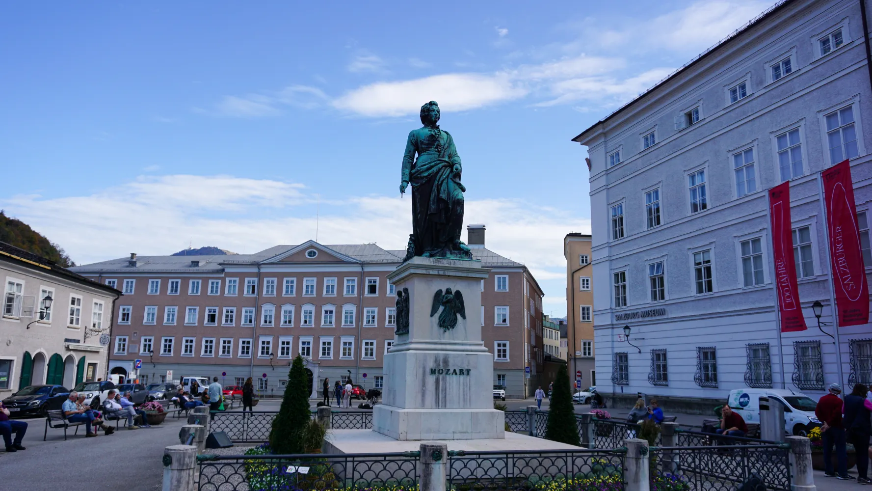 Statue of Mozart on pedestal in Salzburg city square with historic buildings.